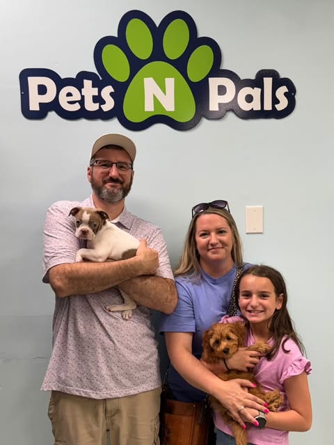 Family holding two puppies at Pets N Pals